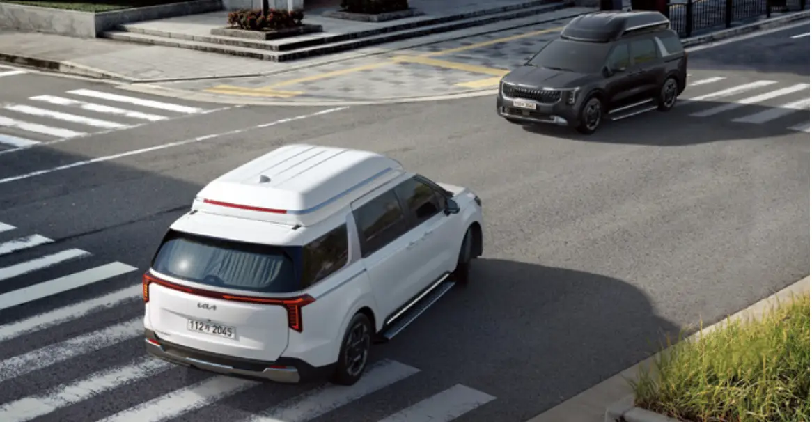 회색 도로 주행중인 흰색카니발 맞은편 검은 Suv차량이 주행중인 모습