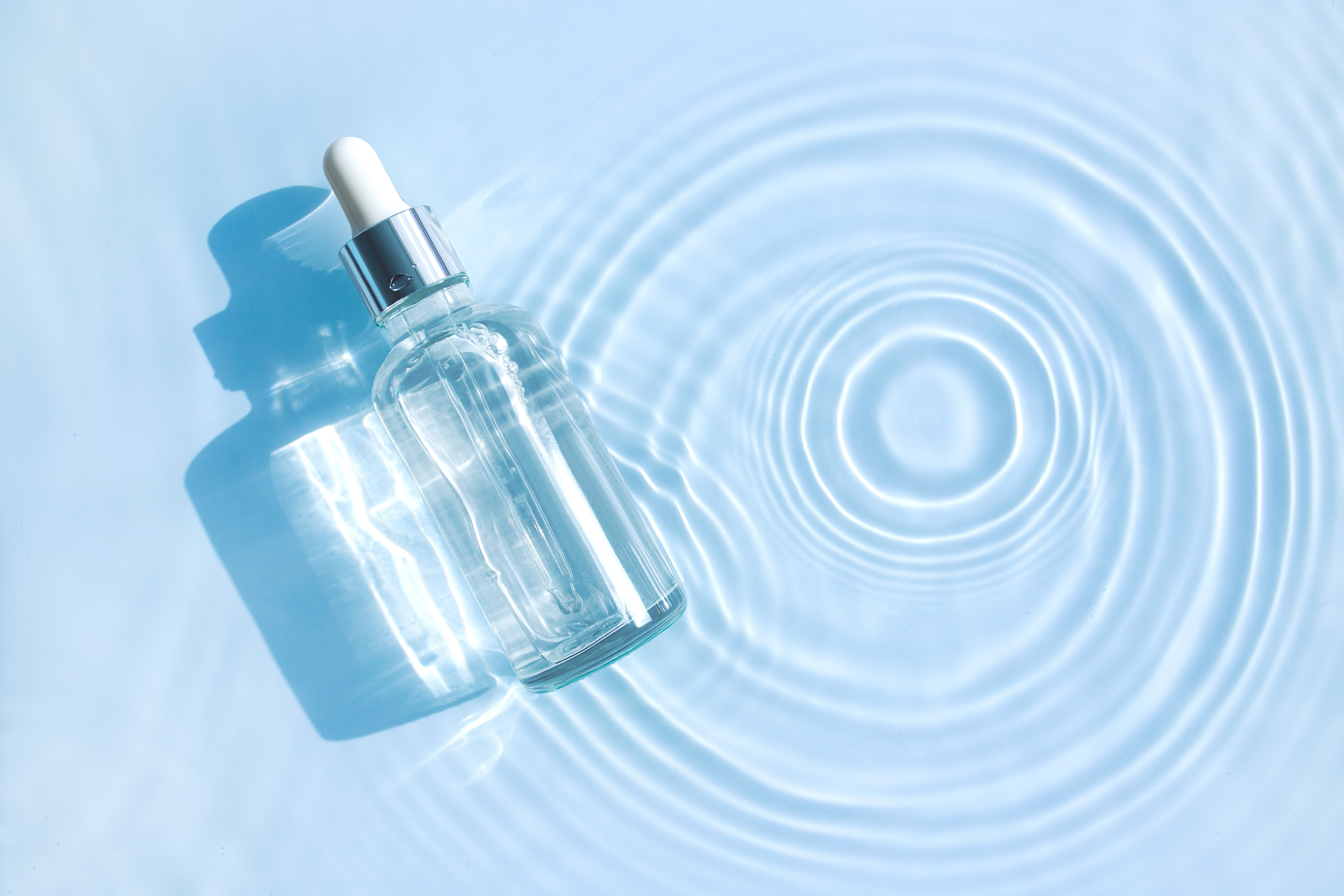 맑은 물결 위에 놓인 여름철 쿨링 효과를 위한 투명한 뷰티 세럼 병