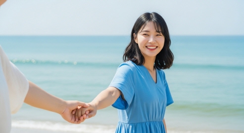 여름 바다 앞에서 손 들고 웃는 여성