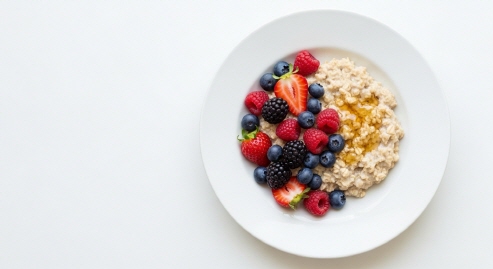 흰 접시에 담긴 오트밀과 과일 아침식사