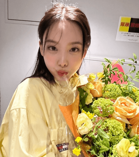 노란 옷과 노란 꽃을 들고 있는 나연