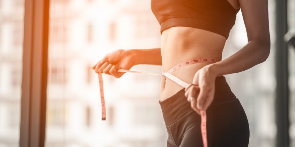 줄자로 허리 둘레를 재며 다이어트 중인 사람