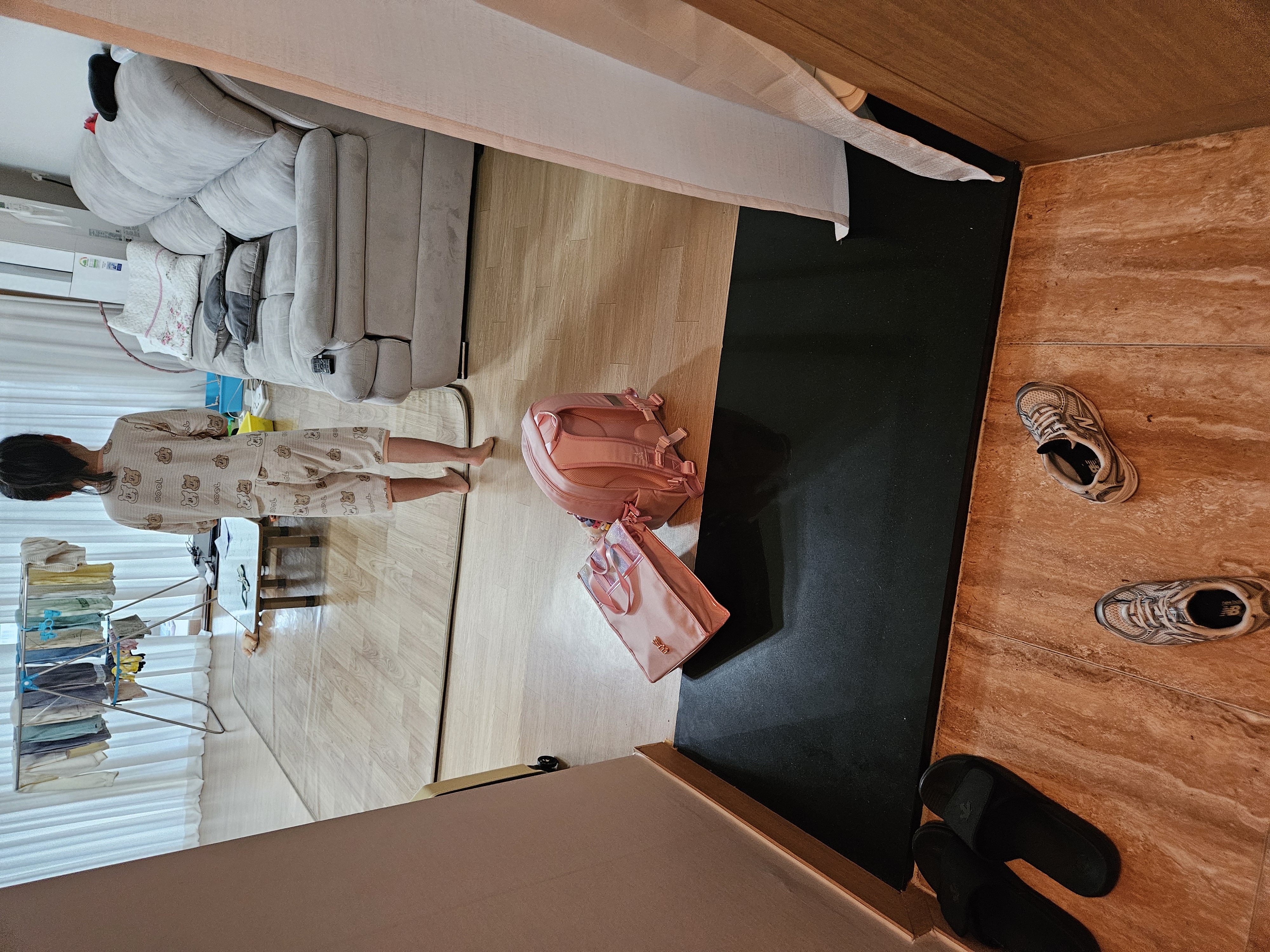 현관 바닥에 무질서하게 놓인 초등학생 책가방, 실내화 주머니, 신발의 모습.