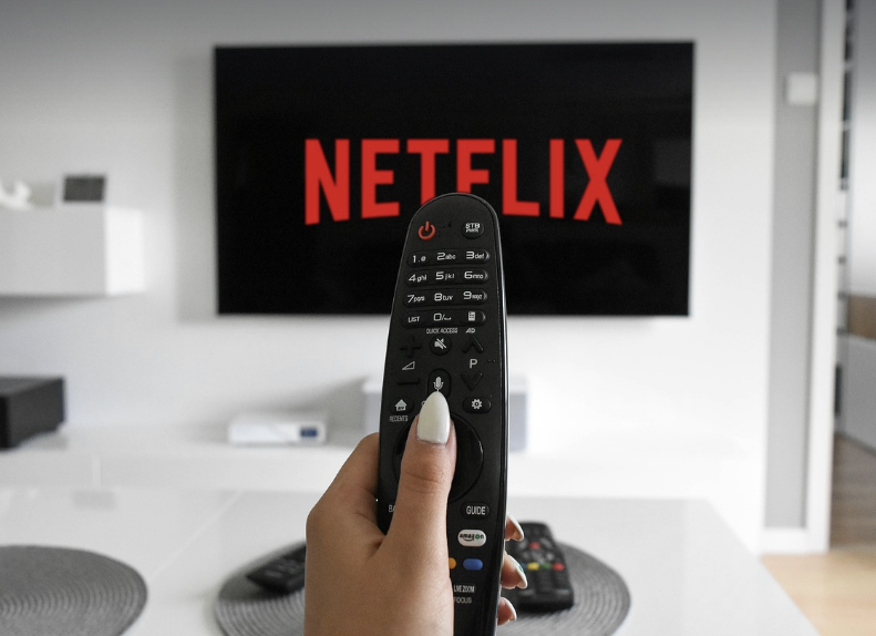 리모콘으로 TV 넷플릭스를 감상하고 있는 사람