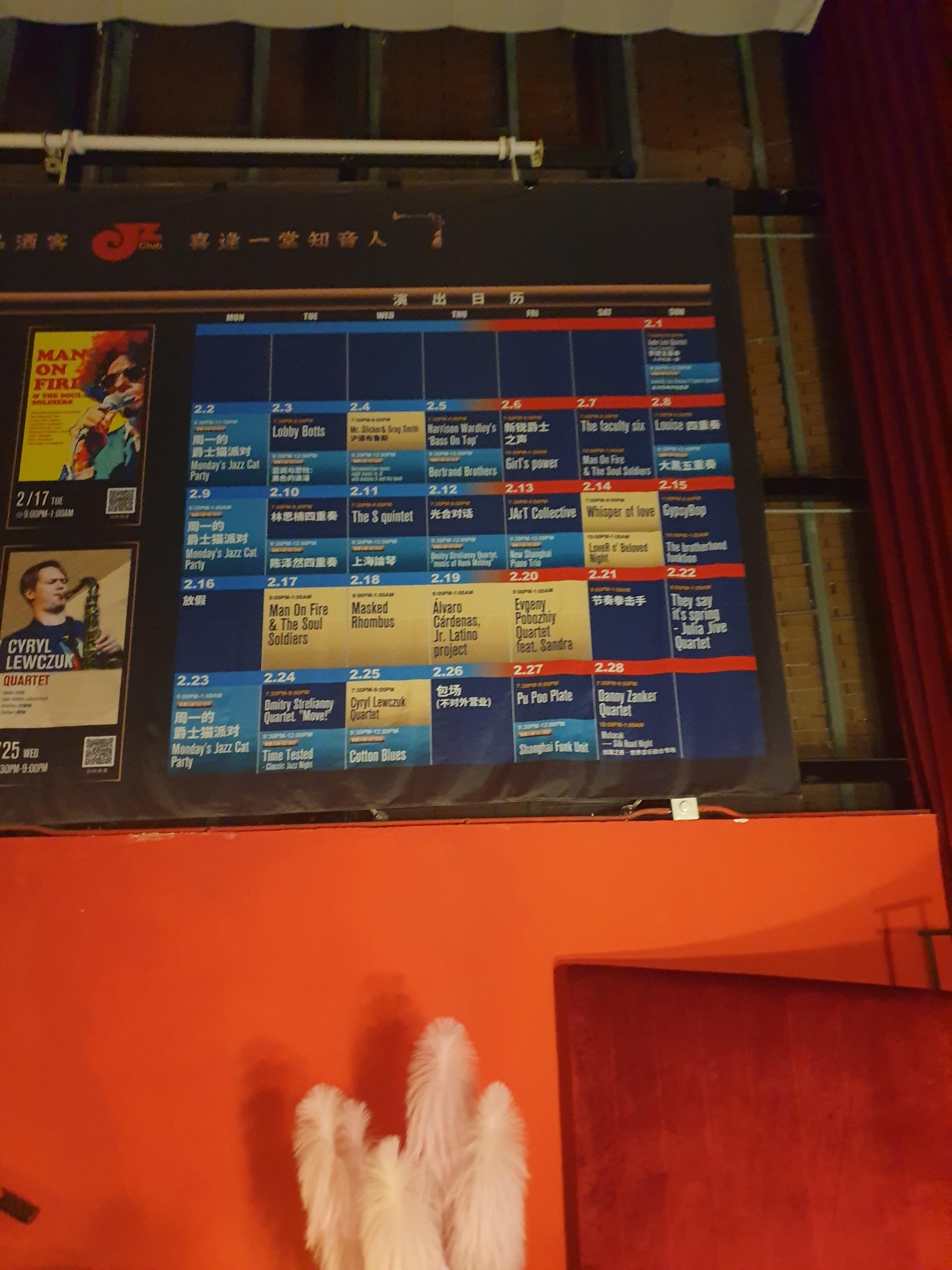 주황색 벽 푸른색 안내판에 공연 일정이 표시 되어 있다.