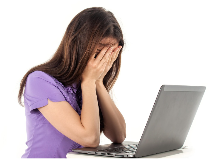 한 여성이 노트북 앞에서 두 손으로 눈을 가리고 있는 모습