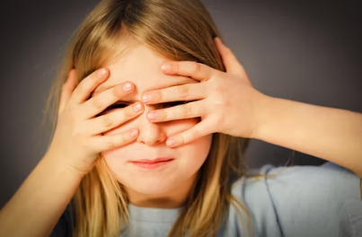 한 소녀가 손으로 눈을 가리고 있는 모습