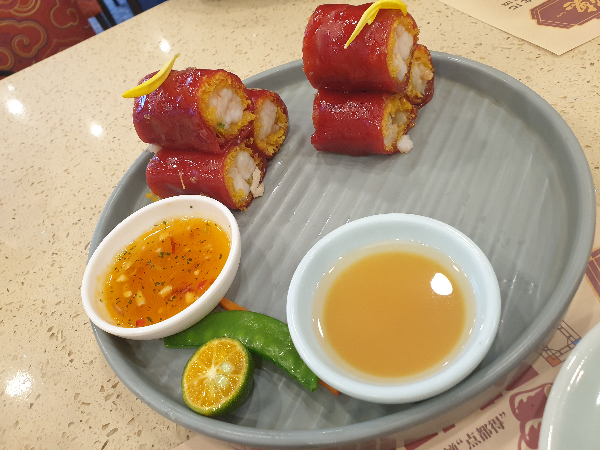 붉은 홍미 쌀피에 쌓인 홍미창펀이 3개 씩 2 덩어리가 놓여 있다. 소스 2종도 함께 보인다.