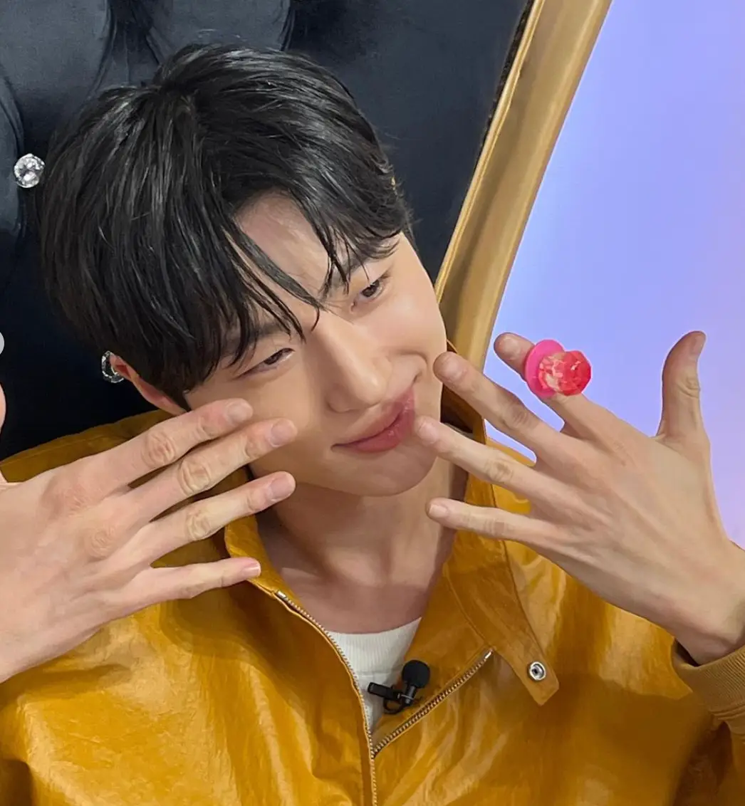 노란 쟈켓을 입고 두손을 얼굴을 가지키며 미소짓는 모습