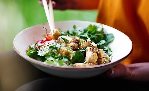 접시에 담긴 샐러드를 젓가락으로 집고 있다.