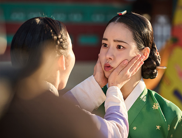 초록색 한복을 입은 임지연의 양 볼을 다른 인물이 감싼 멋진 신세계 스틸