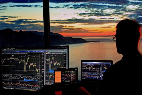 일몰 후 어두운 바다를 배경으로 주식 차트를 분석 중인 트레이더