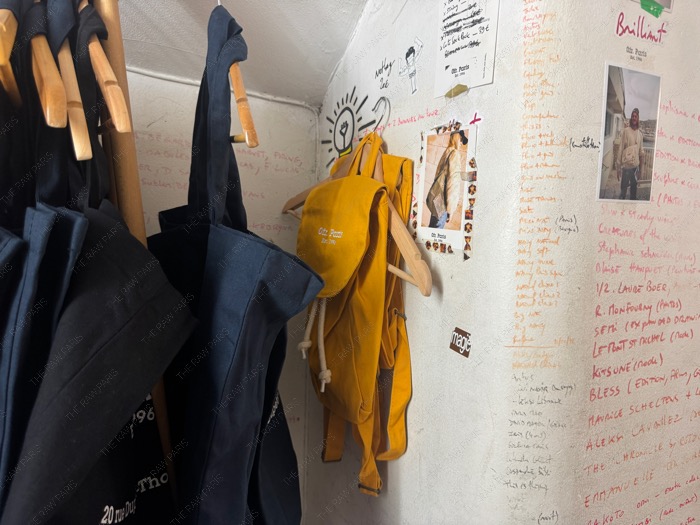 A close up of handwritten walls and yellow canvas backpacks on hangers inside Ofr Paris bookshop ❘ Sac Ofr Paris