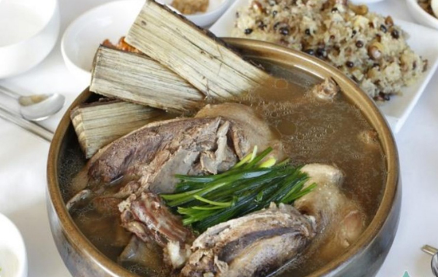 옻나무와 닭을 함께 넣고 끓여서 만든 옻닭은 담은 밤색의 동그란 그릇과 각종 반찬과 밥을 담은 그릇을 함께 놓아두고 찍은 사진