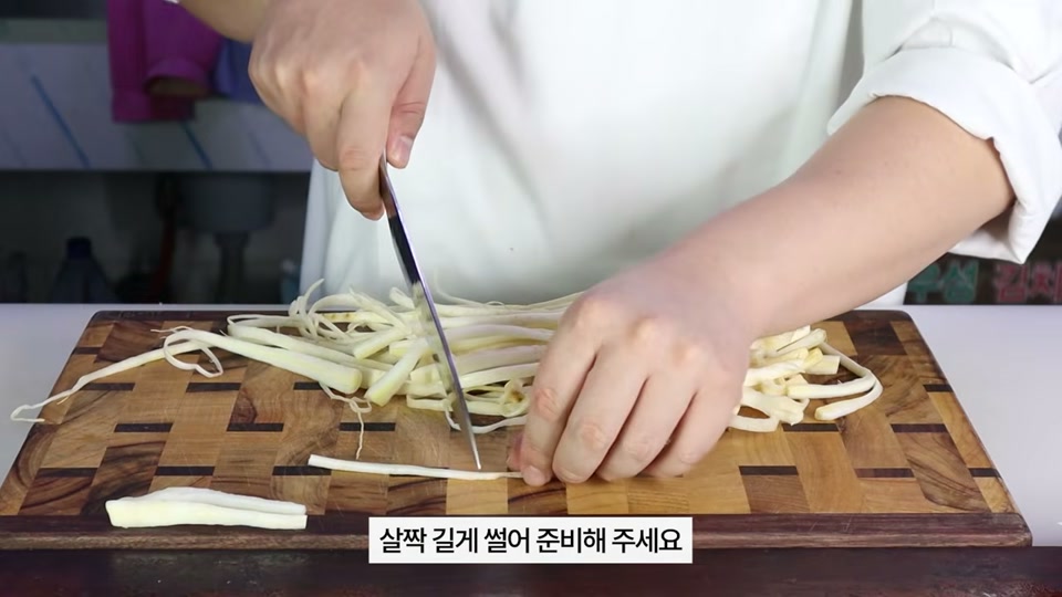 칼로 도라지를 길게 썰어 손질하는 장면