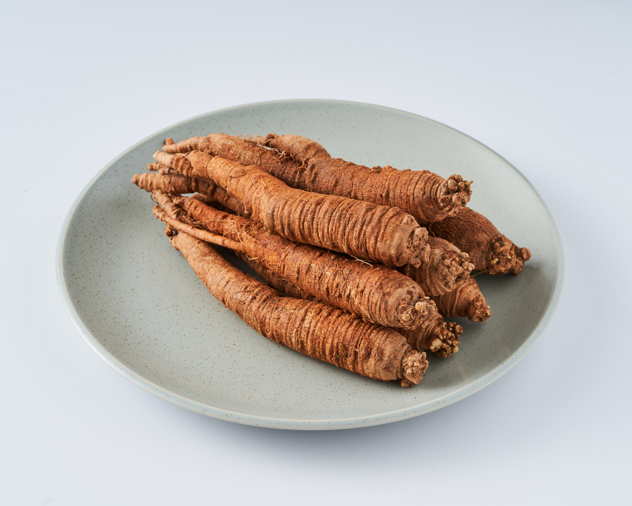 야생에서 채취를 한 더덕을 흰색 바닥 위에 희고 동그란 접시를 놓고 그 위에 8뿌리를 놓아두고 찍은 사진