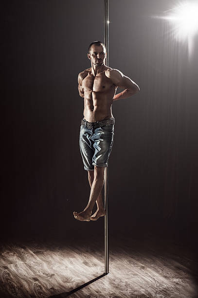 양 팔로만 폴에 매달려 있는 남자 폴댄서