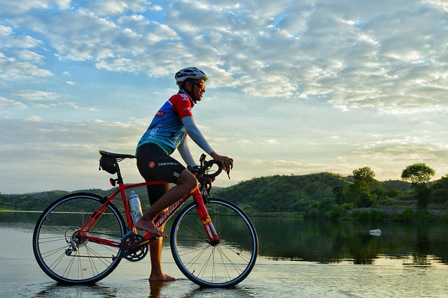 The rider is sitting on a bicycle by the river.