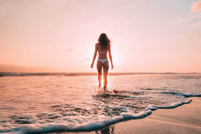 흰색 비키니를 입고 해변을 걷는 여자