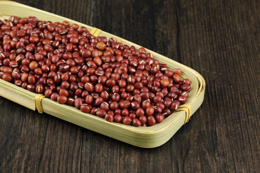 야생에서 채취를 한 붉은색의 팥을 검은 바닥 위에 대나무로 만든 네모난 받침대를 놓아두고 그 속에 수북하게 담아 놓고 찍은 사진