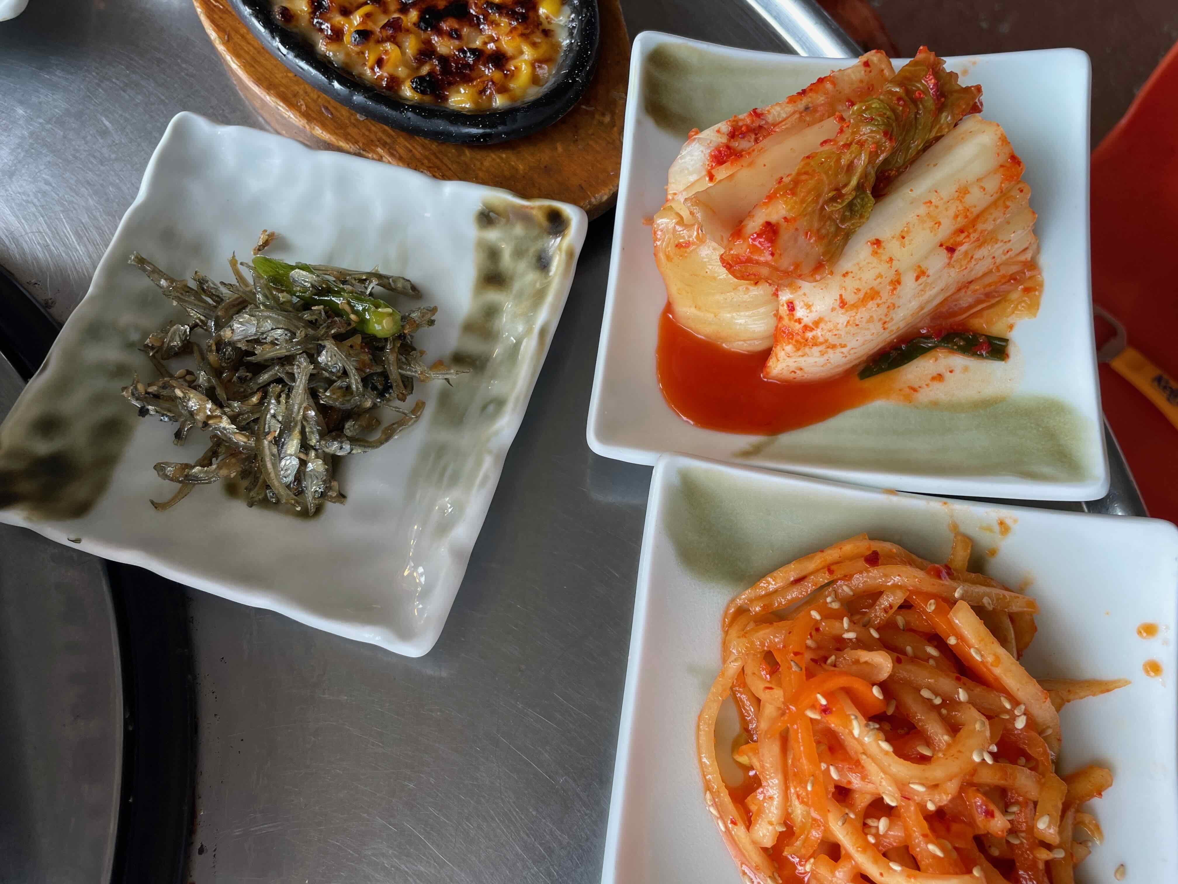 김치, 무생채, 멸치가 흰 접시위에 담겨져 있는 모습