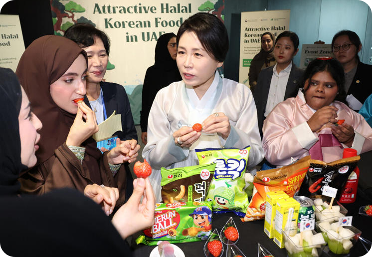 이재명 대통령과 아랍에미리트(UAE)를 국빈 방문 중인 김혜경 여사가 19일(현지시각) 아부다비 주아랍에미리트 한국문화원에서 열린 &lsquo;할랄 케이(K)푸드&rsquo; 홍보 행사에서 참석자들과 한국 과자를 맛보고 있다. [사진=연합뉴스]