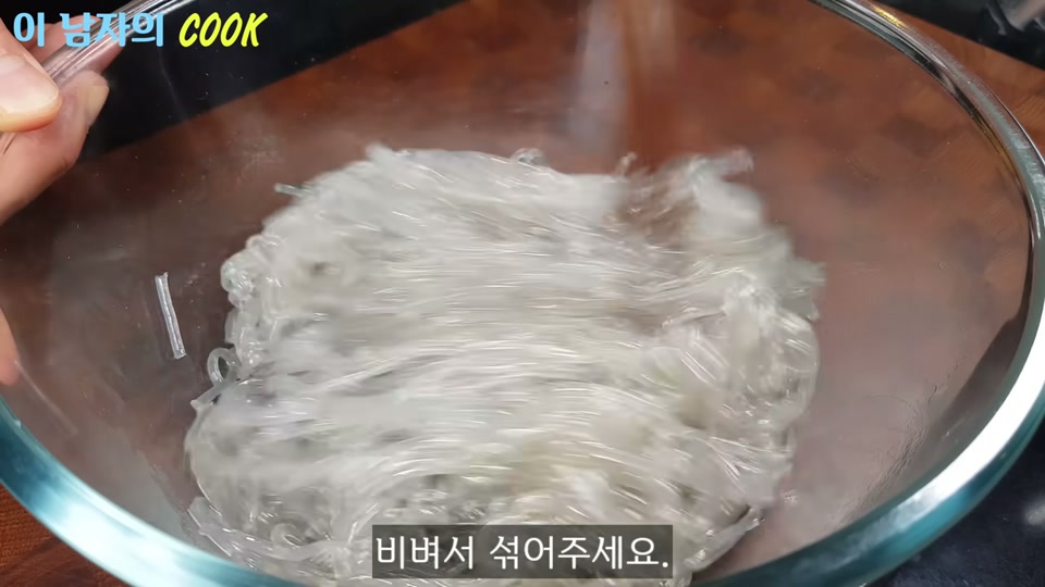 참기름을 넣은 당면을 비벼 섞는 장면