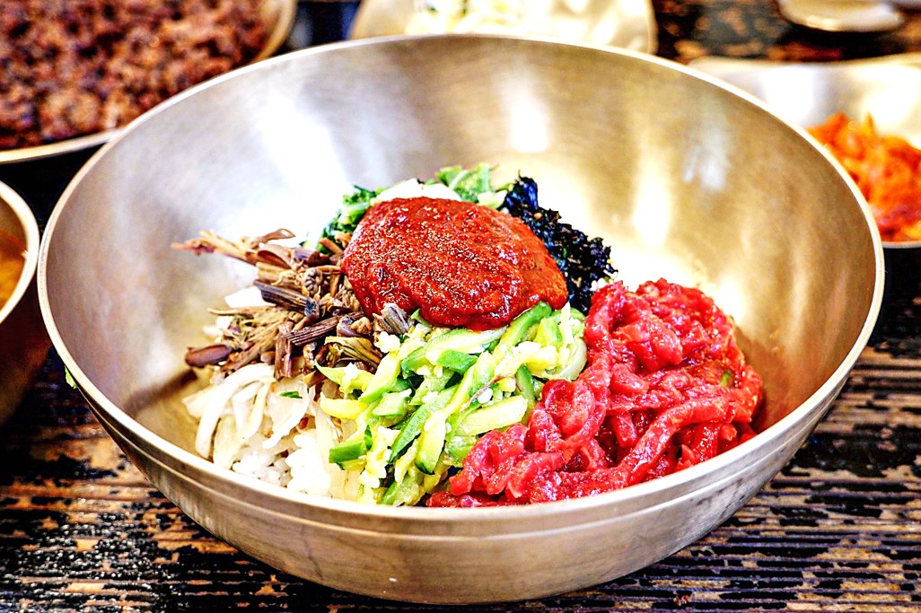 밥 위에 여러가지 제철 나물들과 붉은 고추장, 그 옆에 선홍빛 한우 육회가 가득 올려진 진주 천황식당의 육회비빔밥