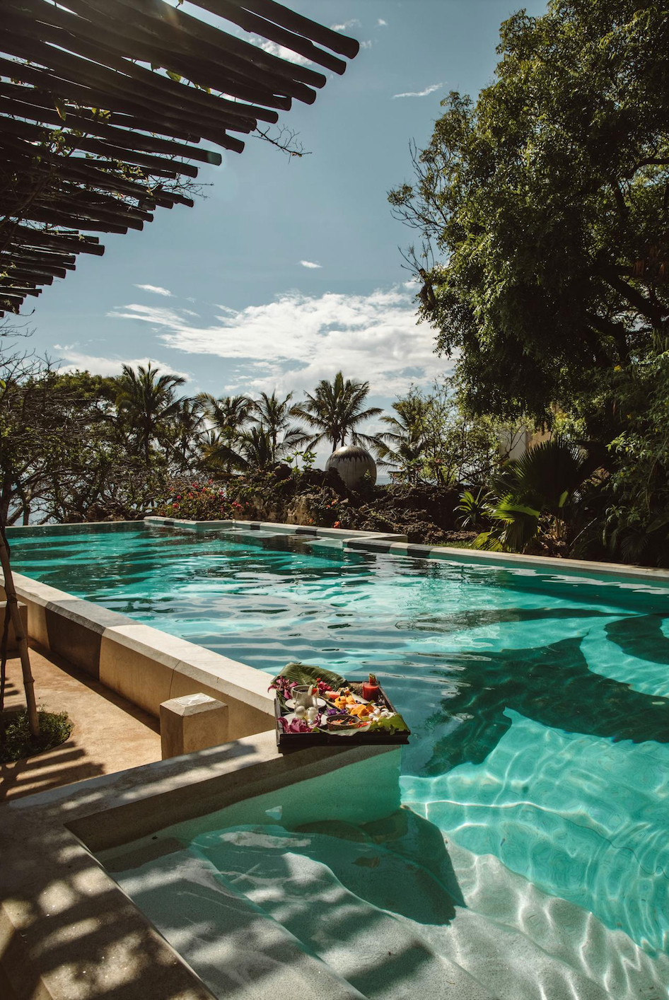 Morning breakfast by a luxury infinity pool overlooking a tropical palm grove
