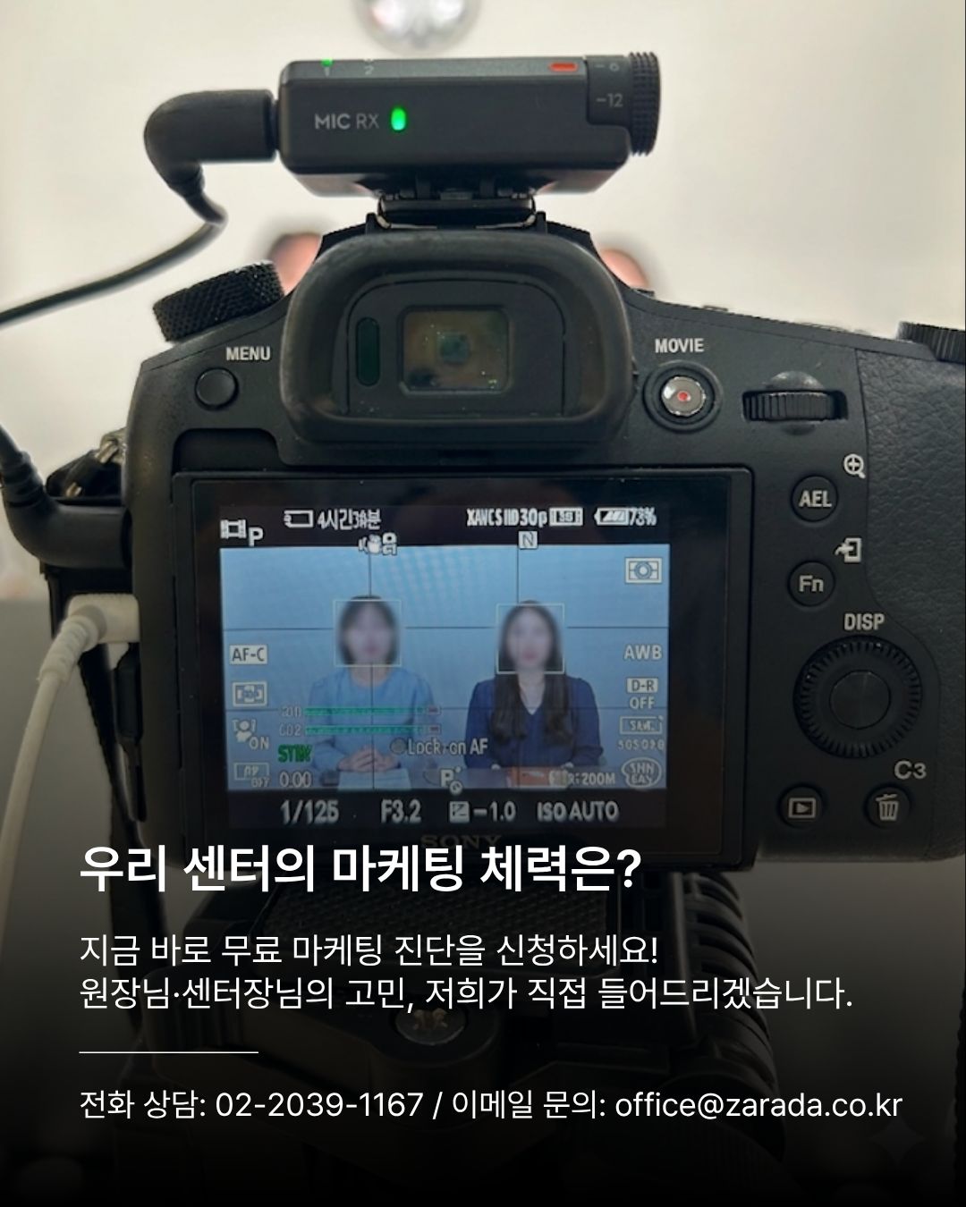 녹화가 진행 중인 소니 카메라의 후면 LCD 모니터 화면을 가까이서 포착한 컷. 모니터 내부에는 두 여성의 정면 인터뷰 격자 구도와 오디오 볼륨 미터가 정밀하게 표시되어 있으며, 하단에는 무료 마케팅 진단 신청을 유도하는 안내와 연락처가 기재되어 있습니다.