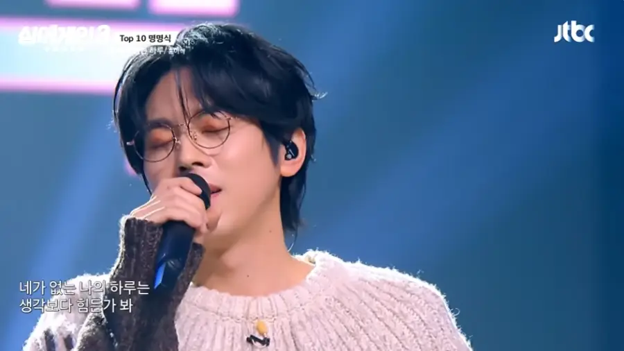 싱어게인3-
파란무대배경 웨이브진 머리 검은색 안경 분홍색 스웨터 검은 마이크를 들고 두눈을 감고 노래하는 58호