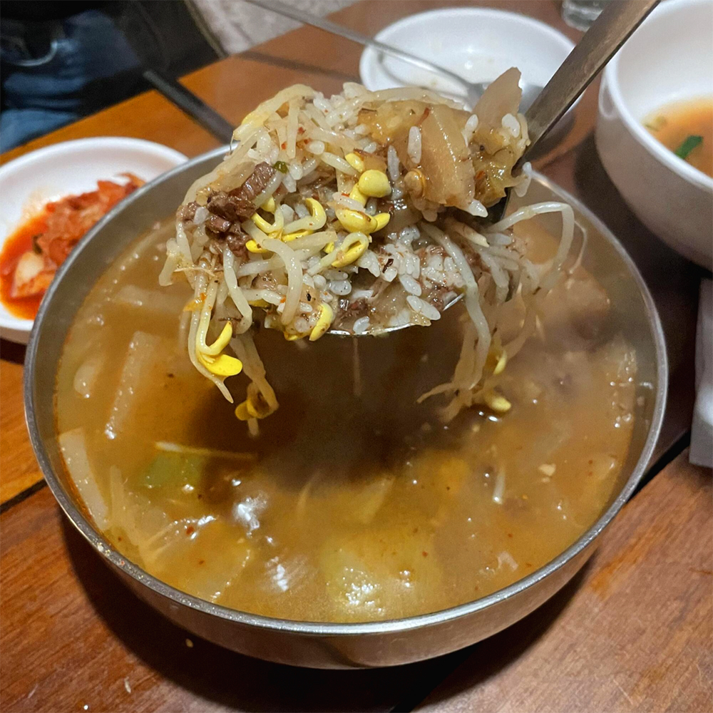 소고기-국밥-위에-국자로-콩나물과-무와-밥을-뜨고-있습니다.
