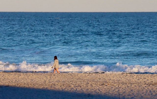바닷가 모래사장을 걸으면서 '걷기명상' 중인 여성 이미지