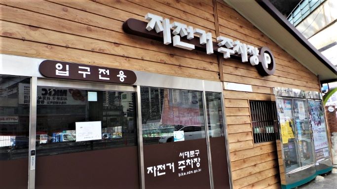 자전거 실내 주차장, 가로 나무판으로 지은 건물벽, 사진은 입구전용 입구,