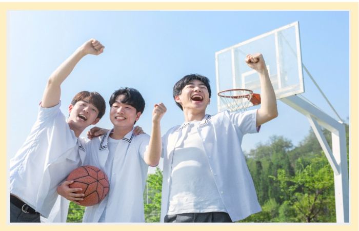 교복을 입은 청소년들이 농구공을 들고 환하게 웃으며 응원하는 모습