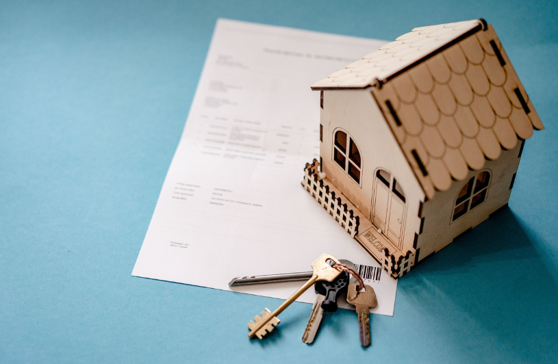 a miniature house with a paperwork and a key
