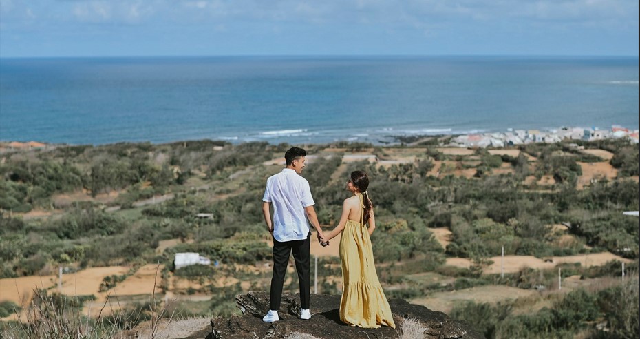 바다가 보이는 언덕위에서 손을 잡고 서있는 젊은 연인의 뒷모습을 찍은 사진