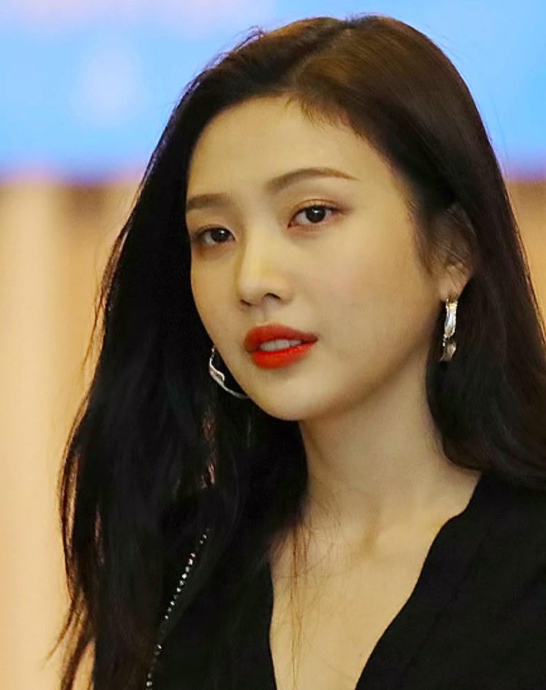 긴 검은 머리에 붉은 립스틱과 큰 귀걸이를 한 여성의 상반신