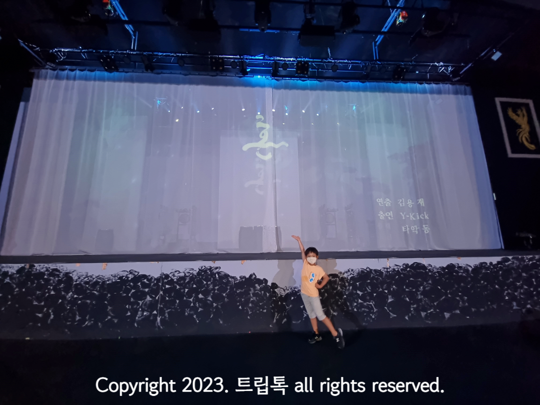 아리랑 혼이라고 적인 커텐쳐진 모대아래 한 아이가 손을 들고 있다