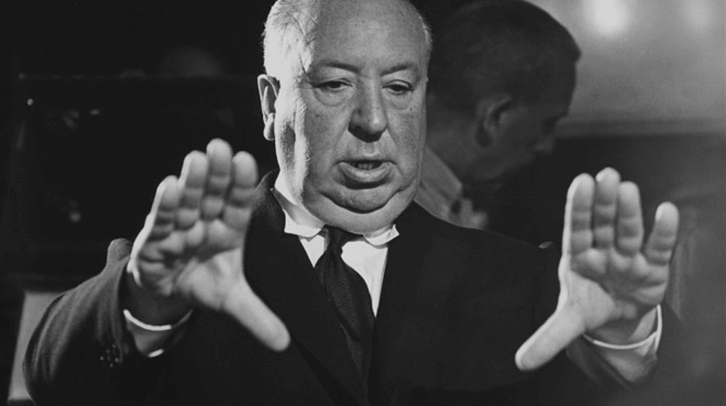 흑백의 사진 알프레드 히치콕 감독 채격이 약간 있는 남자가 두손을 뻗으며 포즈를 취하고 있다.