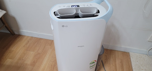 나무 바닥 위에 놓인 흰색 제습기 본체와 상단 송풍구