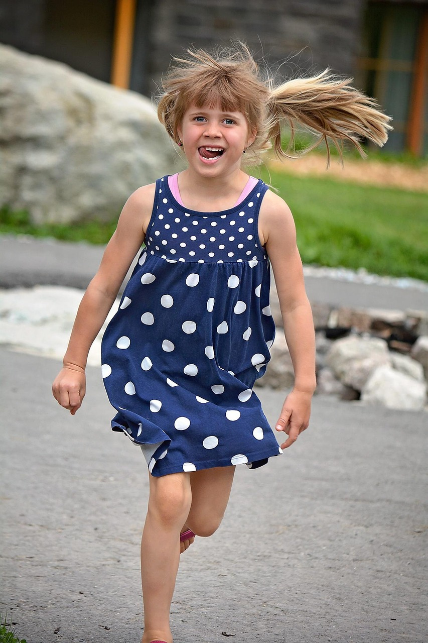 혀를 치아에 가져다대고 뛰고 있는 어린아이