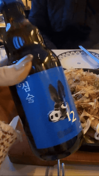 심술 술병을 들고 여름볶음우동과 함께 찍은 장면