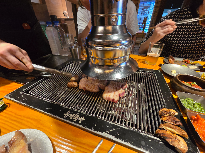 옹기묵방 고기를 굽고 있다. 옹기묵방이라는 글씨가 보인다.