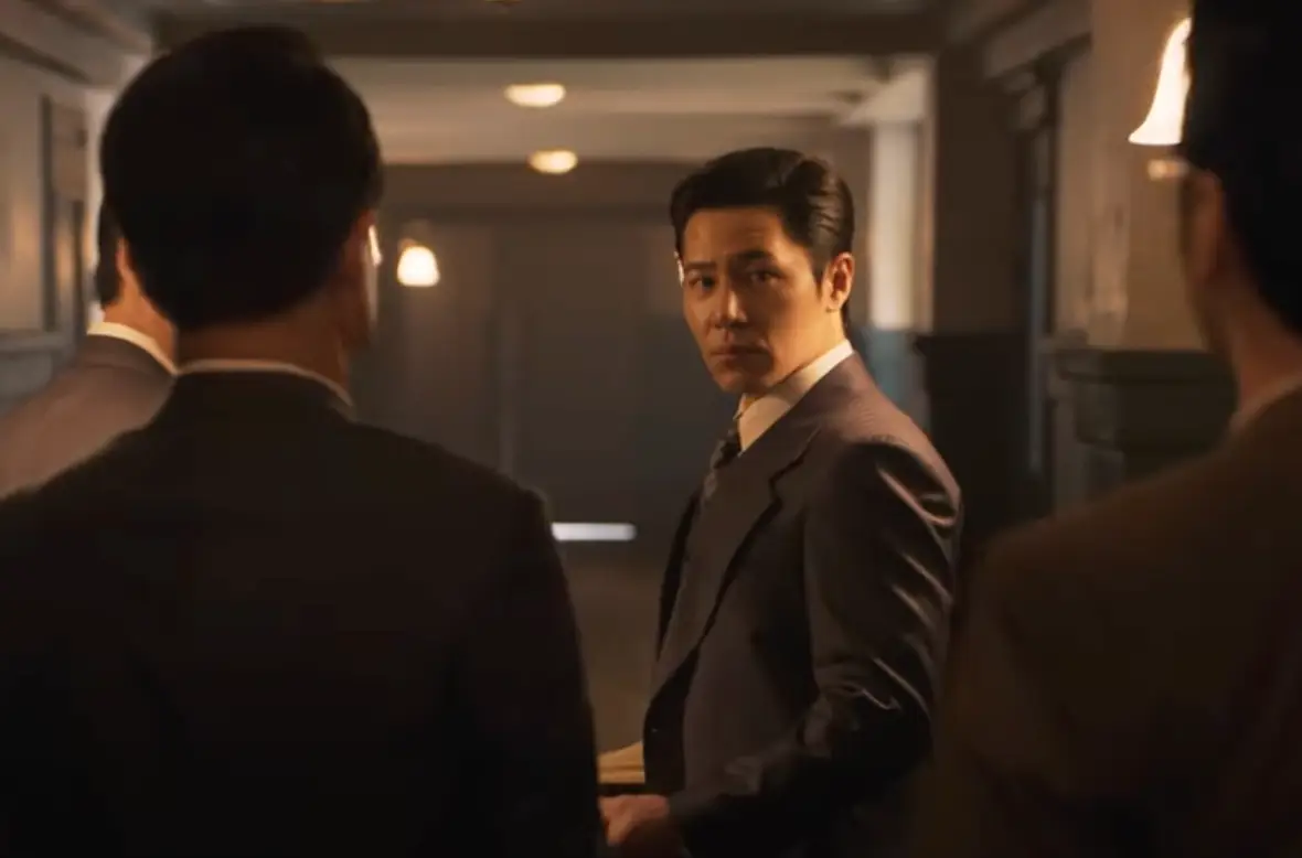 어두운 실내 양복입은 이규형이 화난모습으로 뒤를 돌아보는 모습