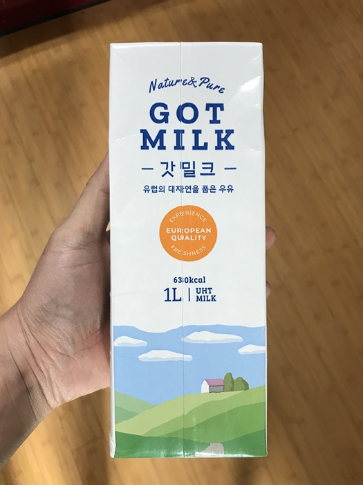 갓밀크 수입 멸균 우유 제품의 전면 패키지 디자인. 1리터 용량의 흰색 패키지에 푸른 목초지 일러스트와 'GOT MILK' 브랜드명이 인쇄되어 있다.