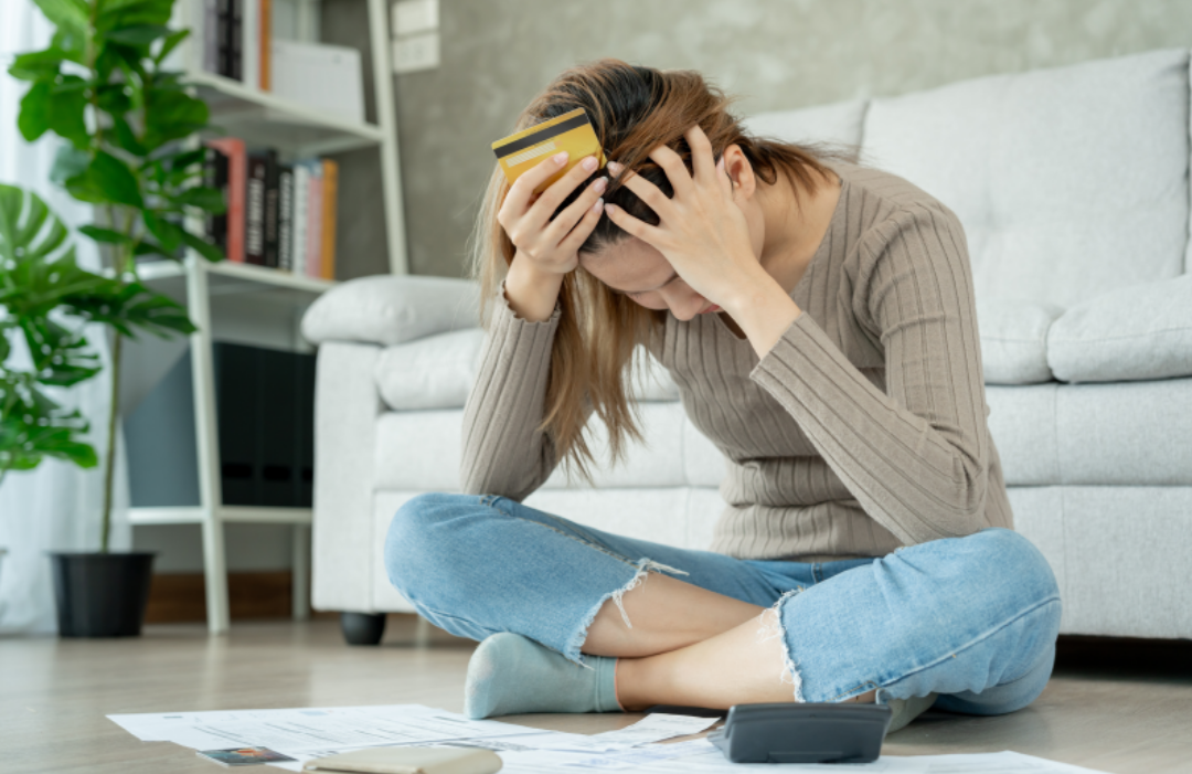 한 여성이 바닥에 앉아 빚으로 괴로워하고 있다.