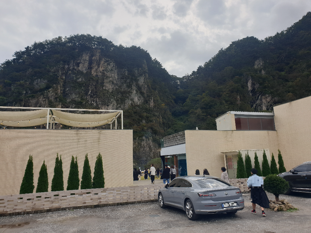 베이직 건물 2개 뒤에 큰 절벽이 보인다. 건물 앞은 주차장이다.