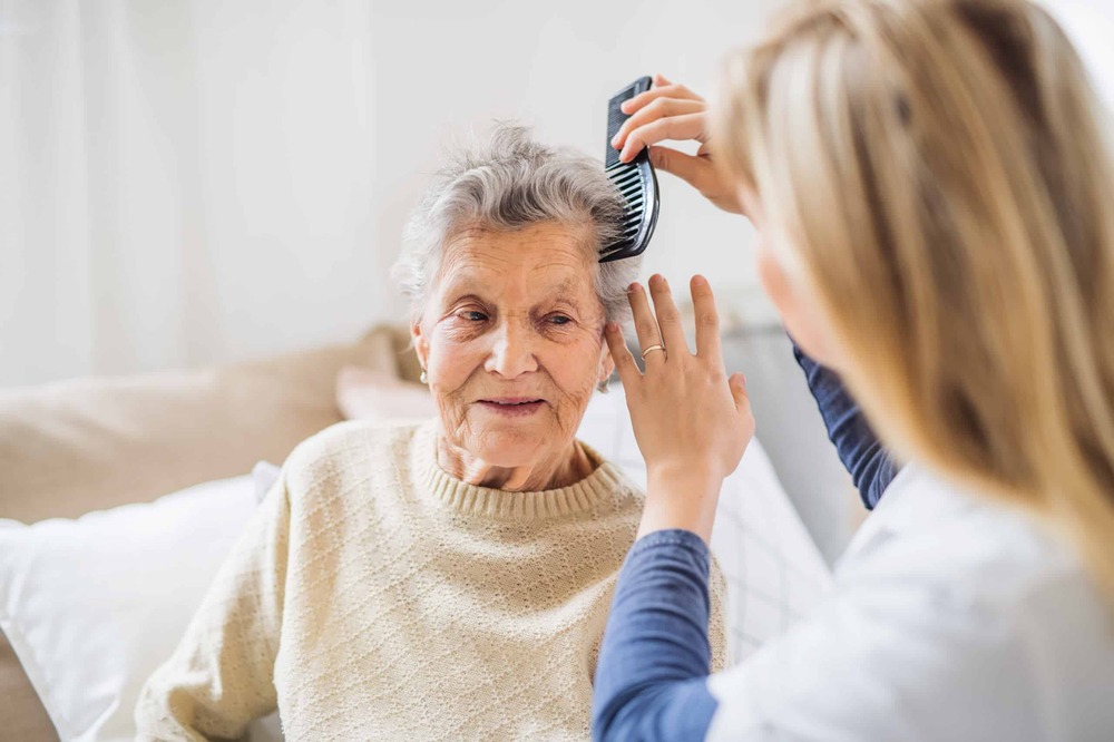 caregiver working in an in home care services agency in Houston, TX doing hair style of her patient