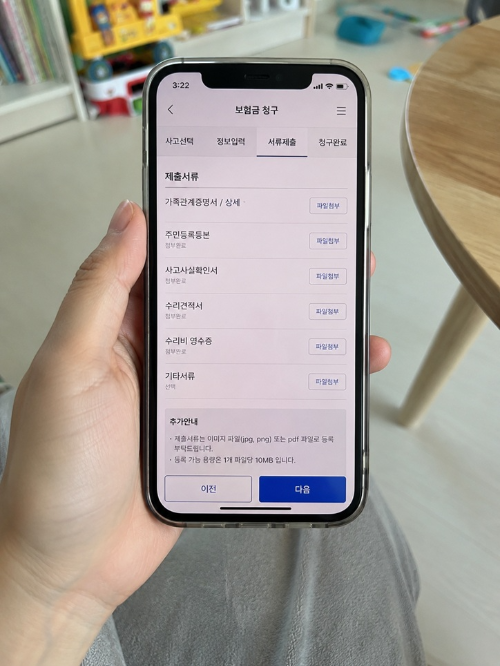 스마트폰 보험금 청구 앱에서 서류 제출 화면을 확인하는 모습